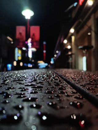 Rain drops on a table with city lights at night behind