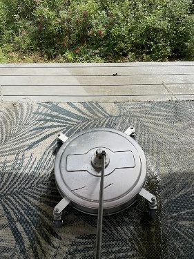 A surface cleaner on a patio with half of it cleaned